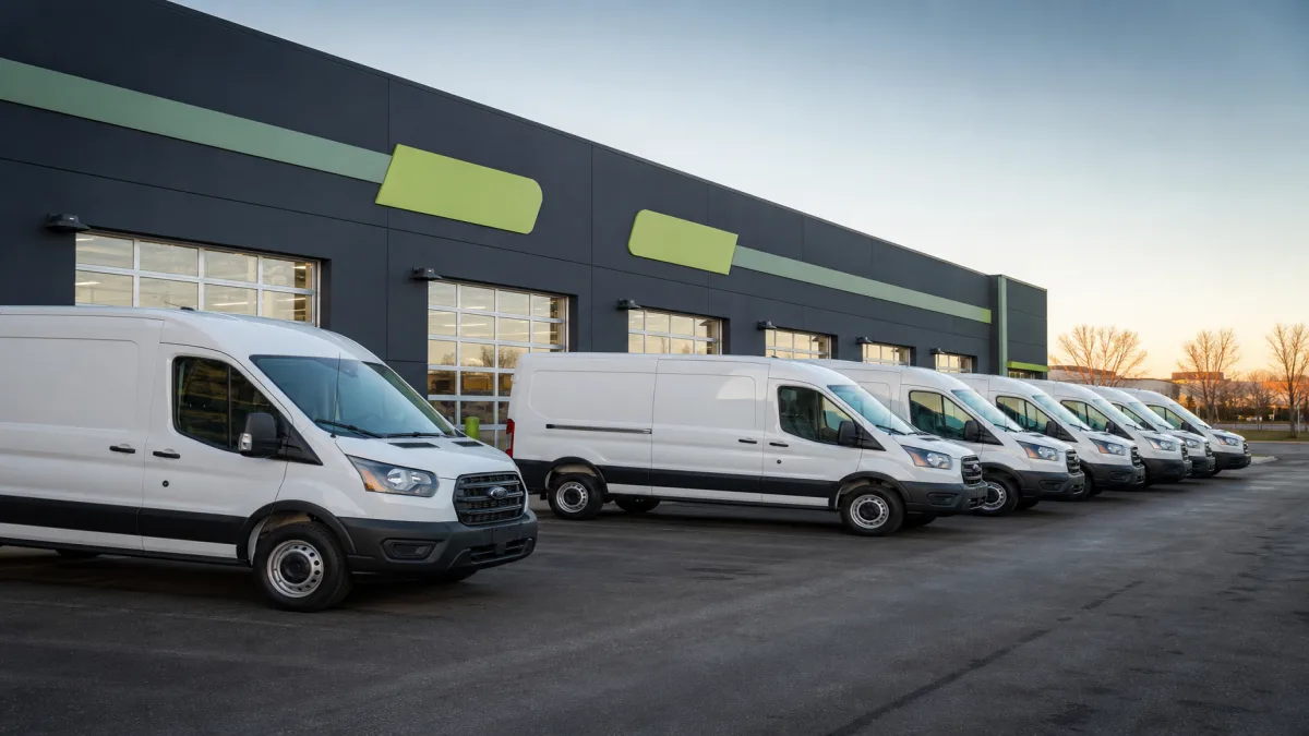 Fleet of commercial vans lined up for scheduled maintenance at a service center, 1200x675
